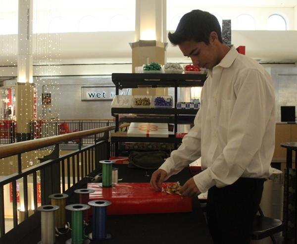 Senior Andrew Lopez wraps presents at the Plaza Camino Real mall on Dec. 14. Lopez and fellow band members wrapped presents for the holiday season as a fundraiser for band. 