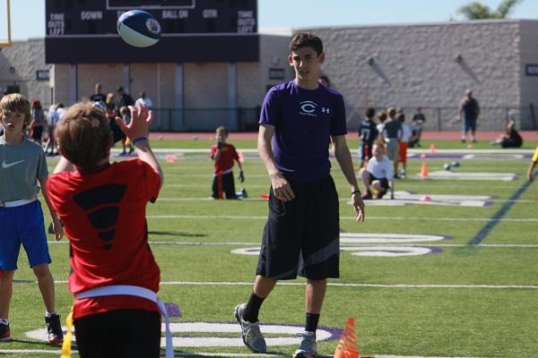 On March 2 freshman Alan Murphy tosses a ball to one of the kids in his small group at the FNL training. FNL is a youth flag football program for kindergarten through eighth grade students who wish to learn how to play flag football.