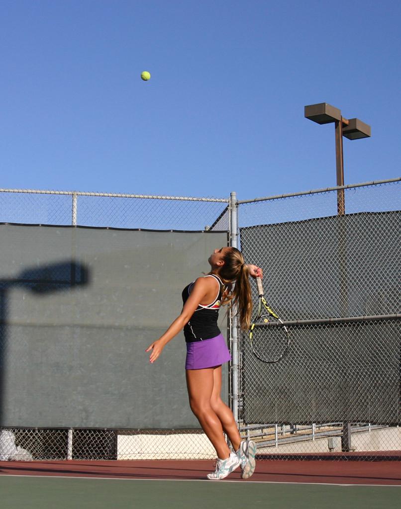 Freshman Alexis Mertz tosses up a tennis ball for a serve during practice on the Girls Varsity Tennis Team.  Aside from balancing academics, Alexis is also the freshman class president and a member on the Speech and Debate.