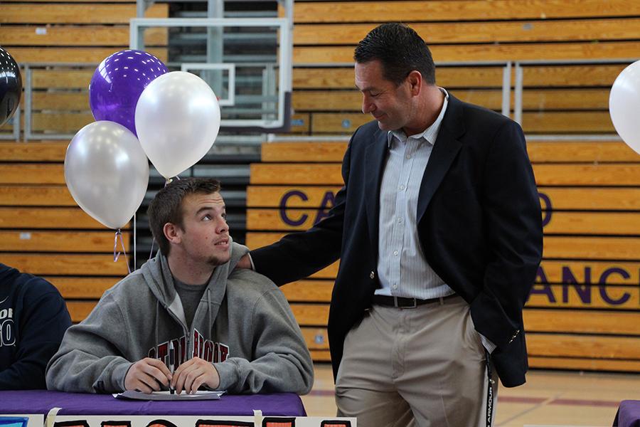 Varsity Coach Mac Neal shares a moment with senior Noah McGinty shortly after the signing. 
