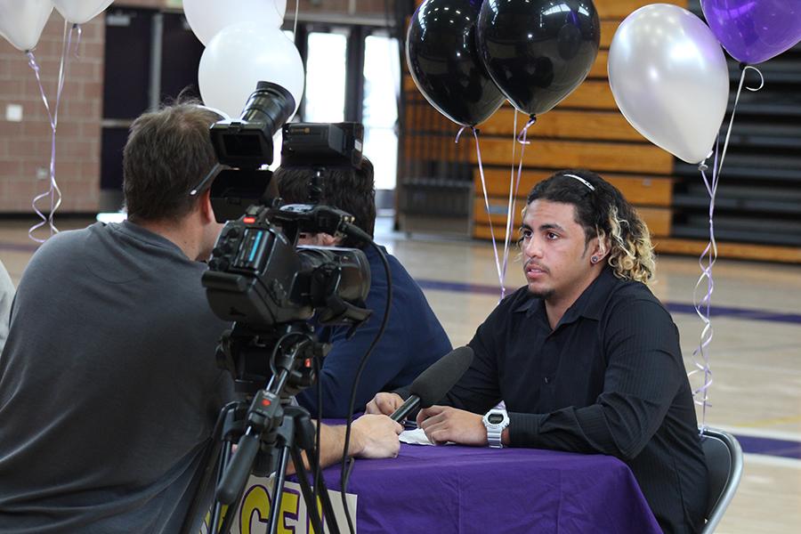 Senior Marcel McGrew gets interviewed shortly after his signing. Cameras continued to flash afterwards to capture the excitement of the players.  