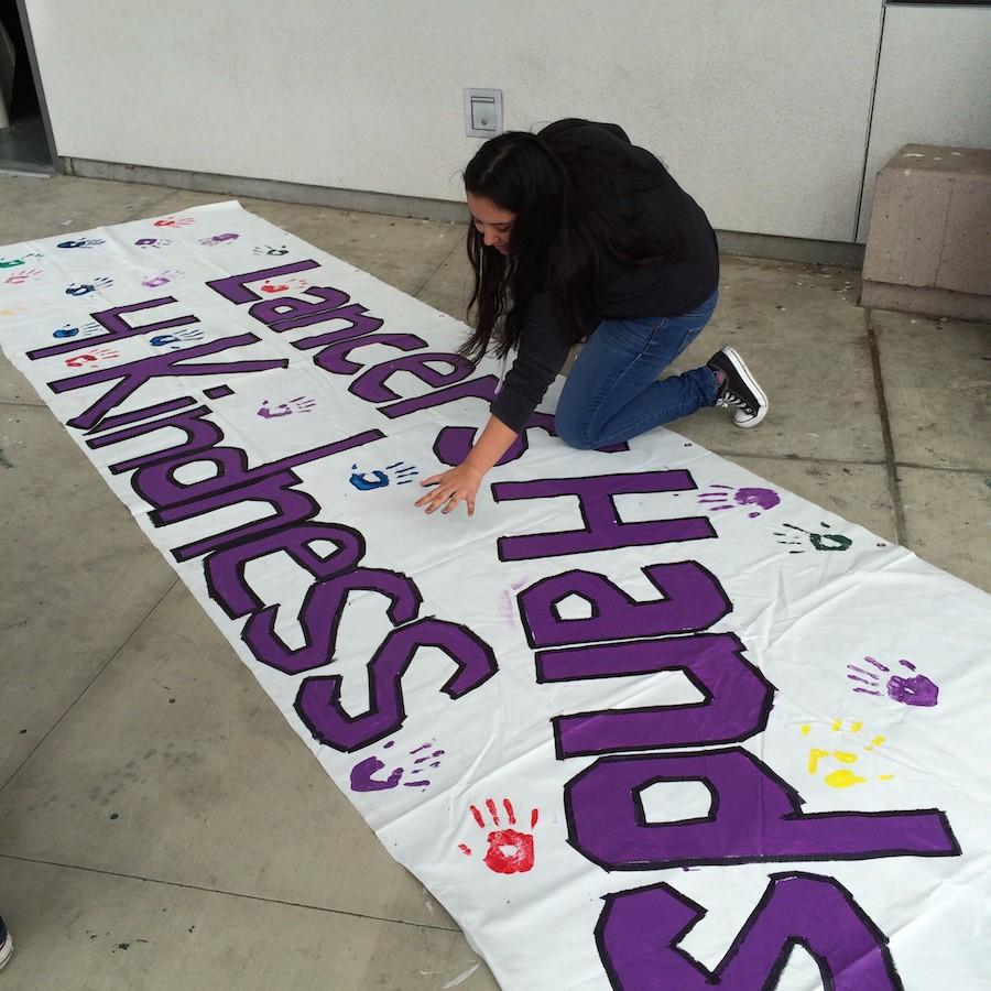 Senior Beenish Ismail adds her hand print to the Lancers Hands for Kindness sign that will go up once it is completed.  This week is the Great Kindness Challenge, a program started by the non-profit group Kids for Peace and promotes simple, and daily acts of kindness throughout this week. 