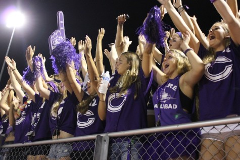Loud crowd members, decked out in purple attire, cheer on the Lancers.