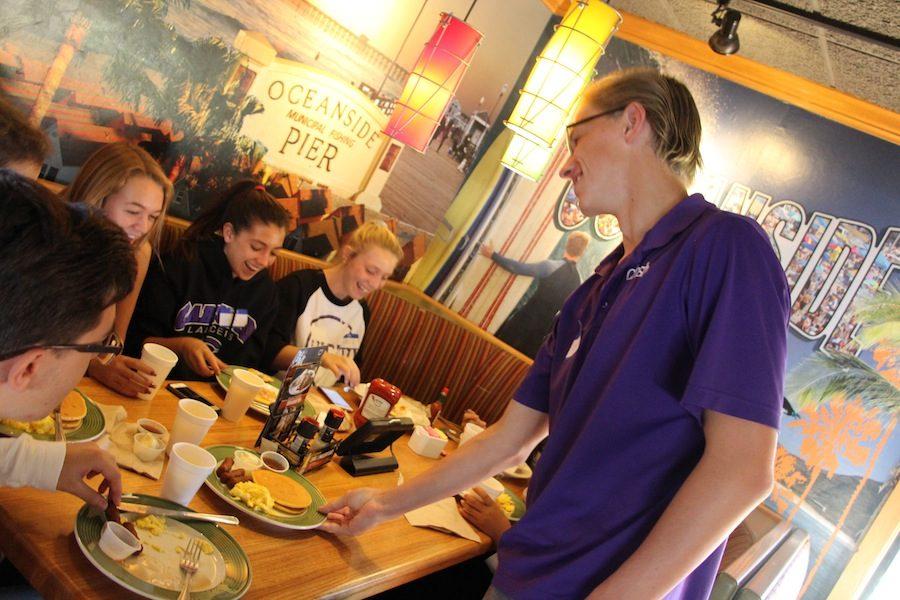 Junior, Connor Hanan, serves breakfast to a table of Broadcasting students. Saturday, October 22, Applebees hosted a fundraiser for Carlsbads Broadcasting students and others.