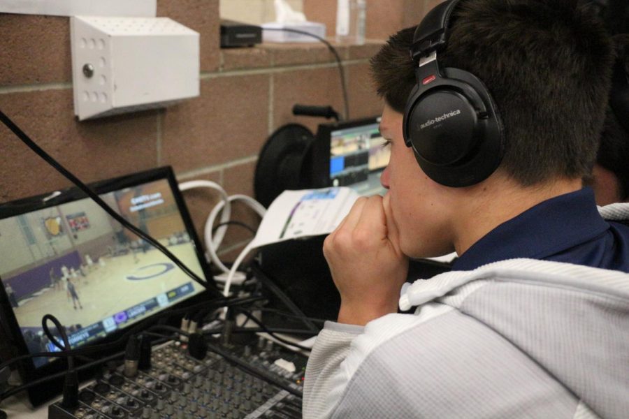 Sophomore Nate Mills views the varsity basketball game on a computer screen as he commentates, Friday, Dec. 1. Mills and senior Peter Kounelis commentated for the CHSTV livestream.