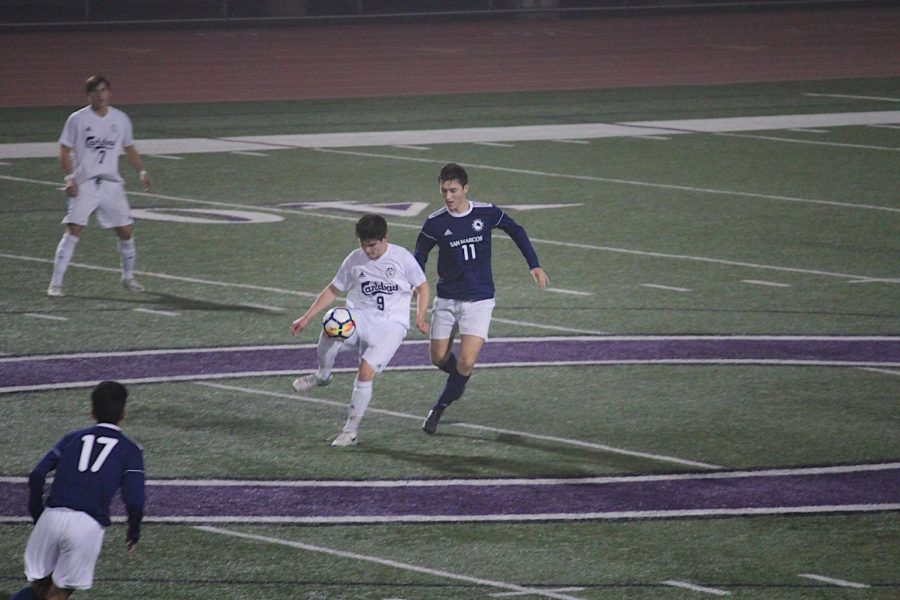 Sophomore Tobias Williams kicks the ball away from opponent during last Fridays varsity soccer game.  San Marcos won with the ending score being 1-0.
