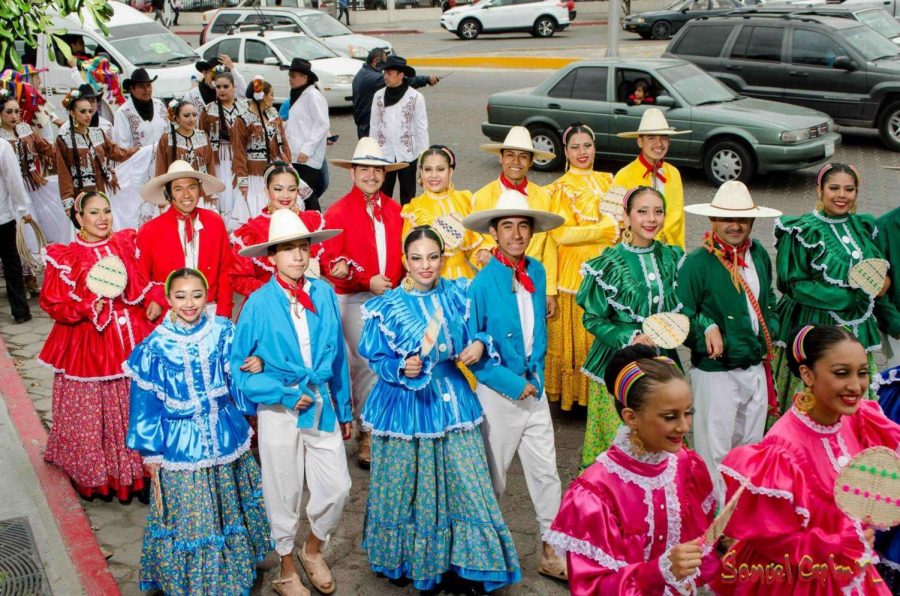 Senior Stephen Alvarado, in the blue costume on the right, walks through town with his dance group during a performance.