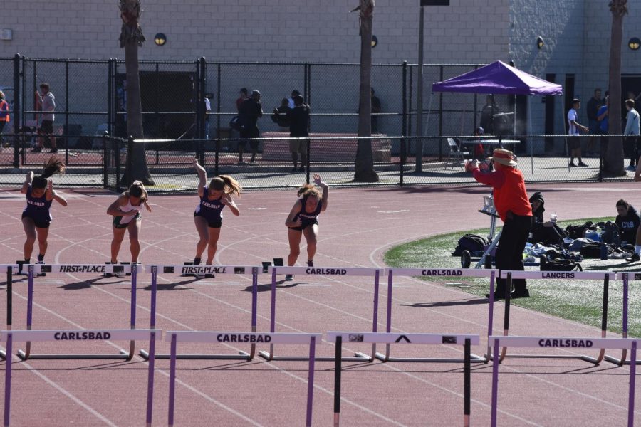 Juniors Rachel Medina and Zoe Nolte and Freshman Olivia Lewis sprint to the hurdles during the 100 yard hurdle event. The event is started from the sound of a blank gun shot.