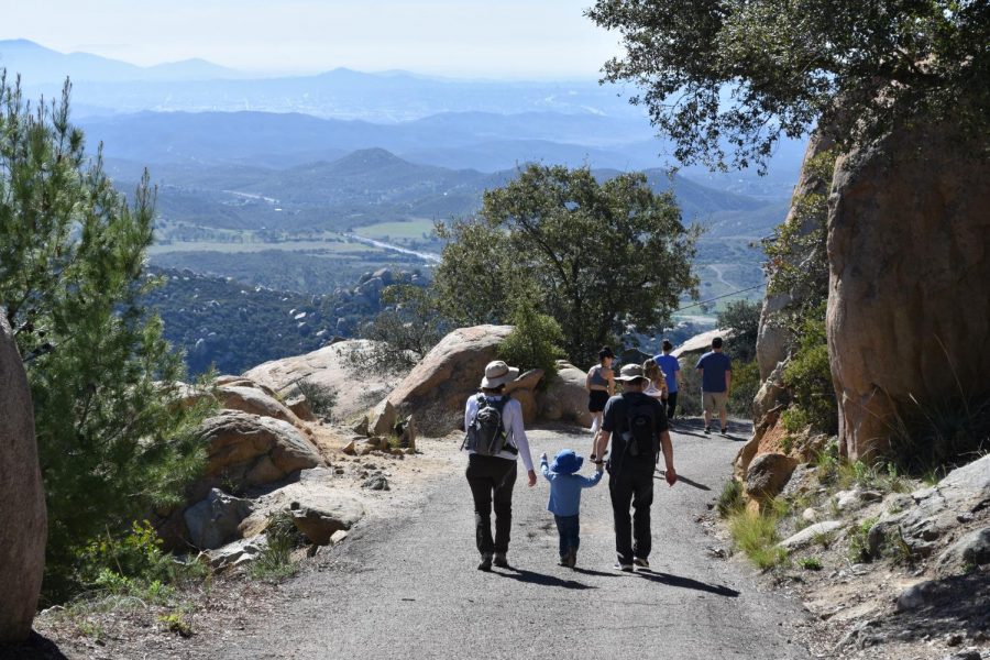 A family hikes down the mountain after seeing the famous rock. Although the hike is difficult people of all ages can complete the hike.