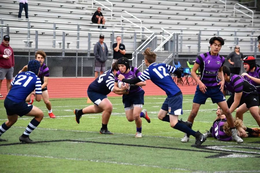 Sophomore+Solomon+Williams+runs+up+the+field%2C+rugby+ball+in+hand.+Williams+plays+scrum-half%2C+a+position+often+compared+to+quarterback.