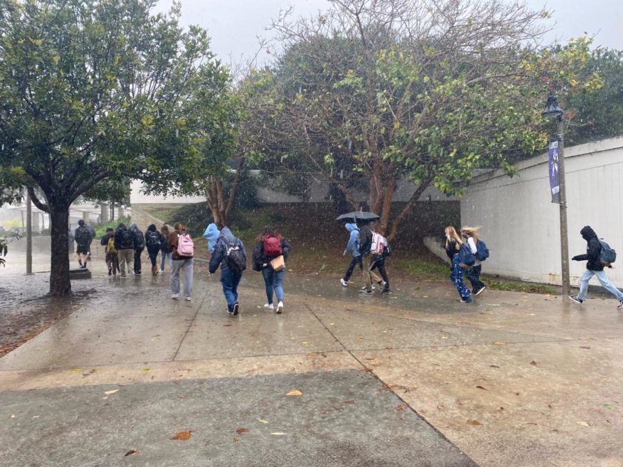 Students run out in the rain with their umbrellas and hoods, hoping to find a dry place to enjoy their lunchtime.