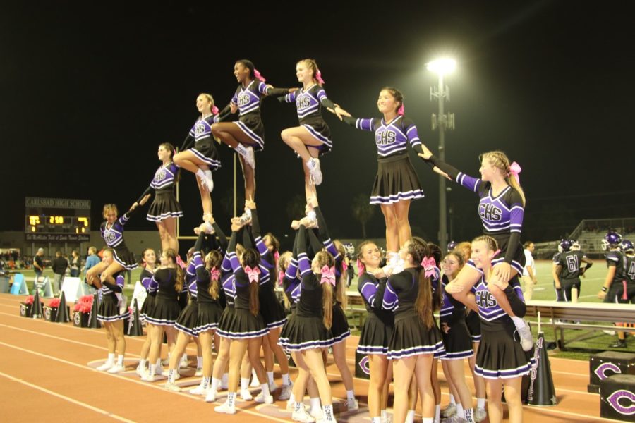 Carlsbad Cheerleading puts up a stunt after another Lancer touchdown during the Pink Out themed home football game against Oceanside High School.