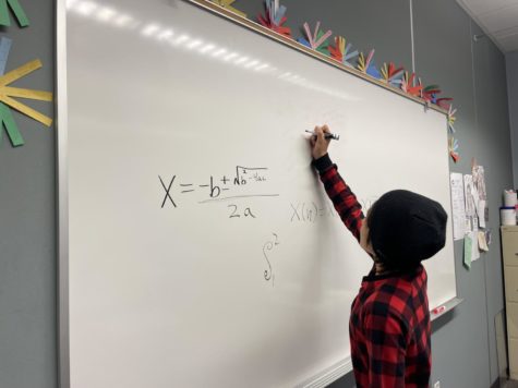 Seventh grader, Max Kroll, writes the quadratic equation on the whiteboard. The quadratic equation is a crucial part of Algebra and Precalculus.