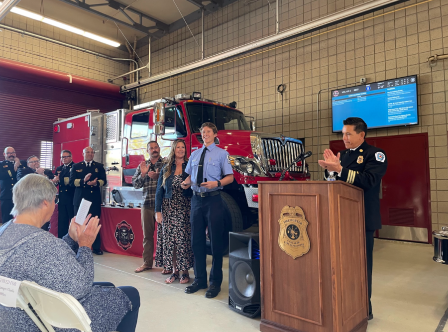 Vanderhorst stands to receive his award at the Carlsbad Fire Department while family, friends, and firefighters cheer for him.