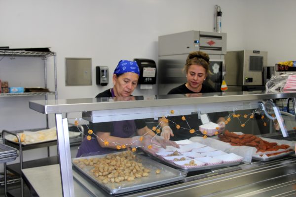 Cafeteria workers Leticia Correa and Maria Moreno cook lunch for students.