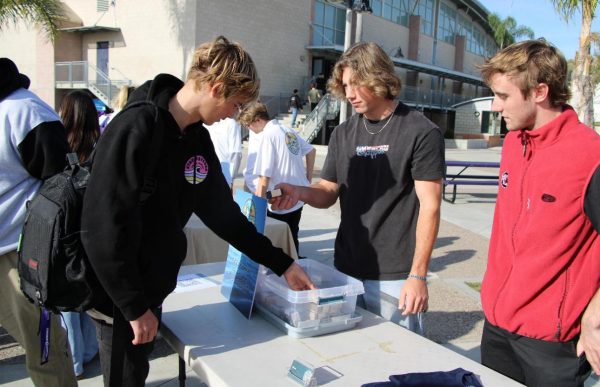 At CHS Lancer Market, students gather at a teen's small business to gain knowledge about their product.