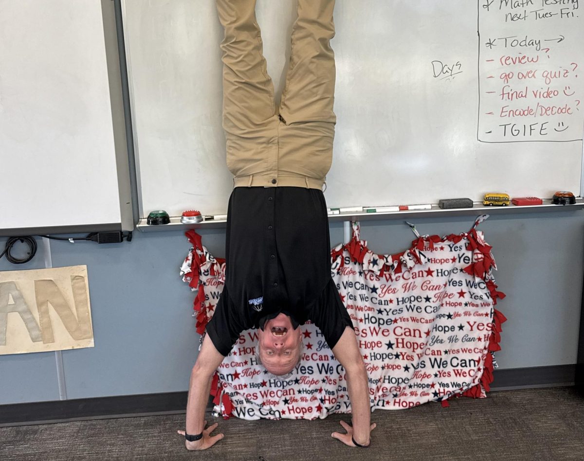 Math teacher Mr. Ogden doing a handstand in front of his "Yes I can!" blanket.