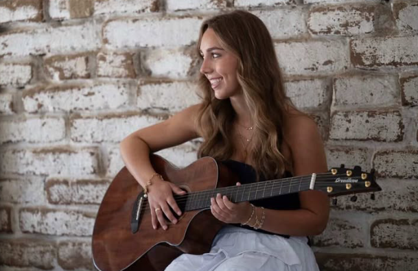 Aryana playing the guitar for an audience.