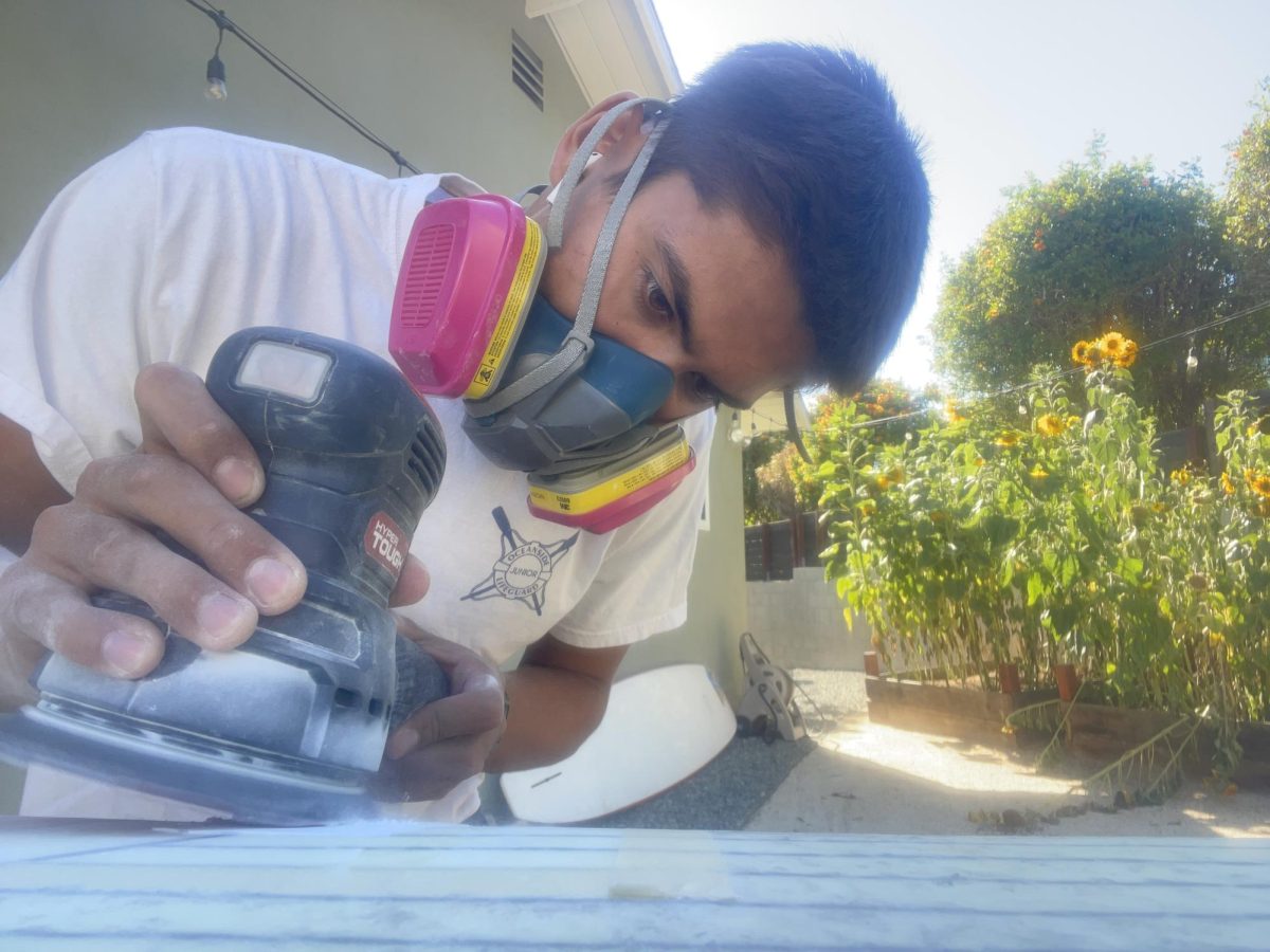 Rosete sanding down a surfboard for his business.